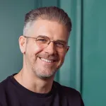 Portrait of Martin Gratzer smiling, wearing glasses and a dark sweater
